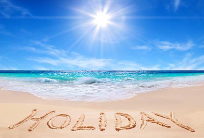 The word HOLIDAY written in sand beside a heart at the beach